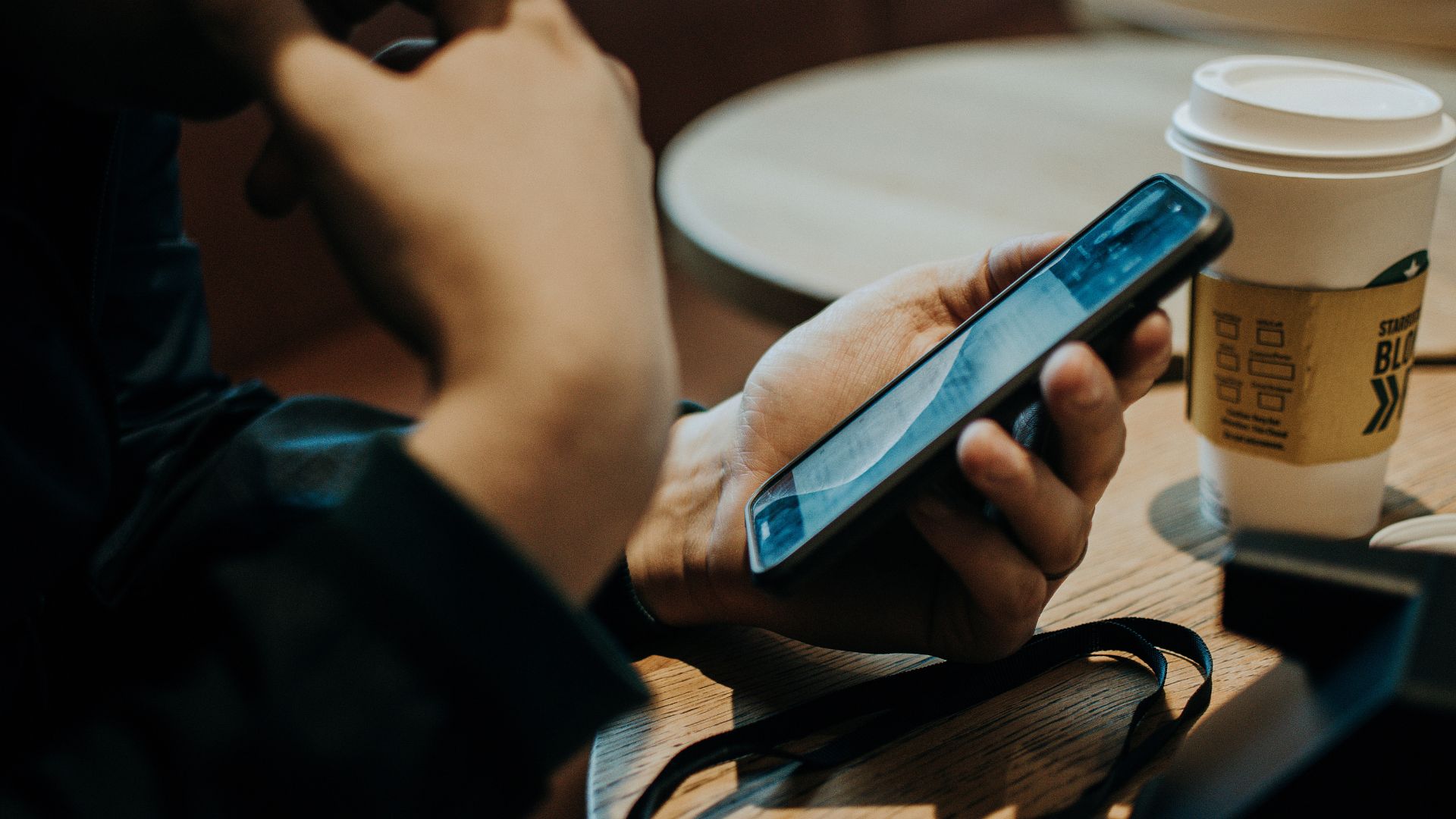 A person checking their phone over morning coffee at a café
